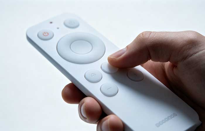 Finger pressing low force silicone keypad on a white smart remote control