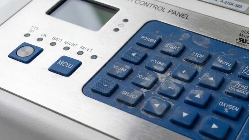 A dusty blue silicone keypad with visible fingerprints and grime mounted on a stainless steel control panel
