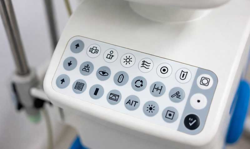 clean white laser etched silicone keypads with crisp high contrast medical icons and symbols on a modern medical device control panel under bright clinical lighting