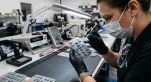 A tester is inspecting a gray waterproof silicone rubber keypad during the testing process