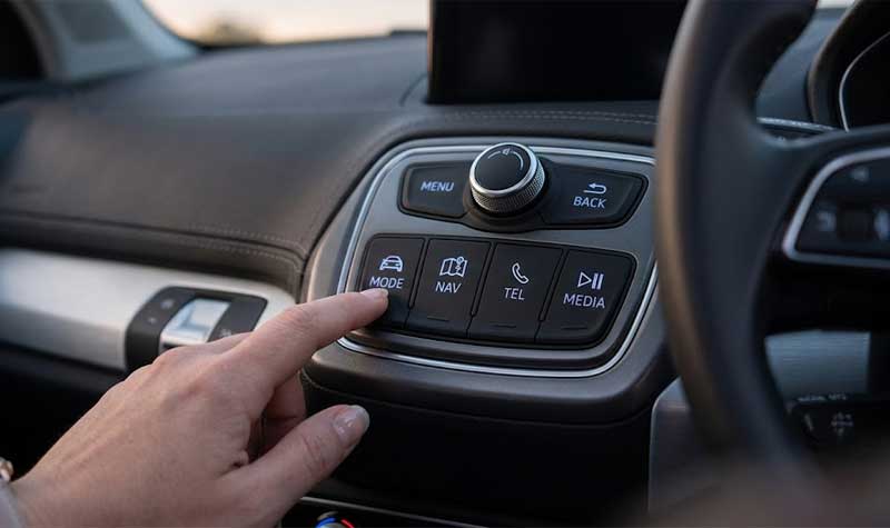 An individuals hand pressing a MODE switch on a modern automotive control panel featuring backlit conductive silicone buttons designed for vehicle dashboards