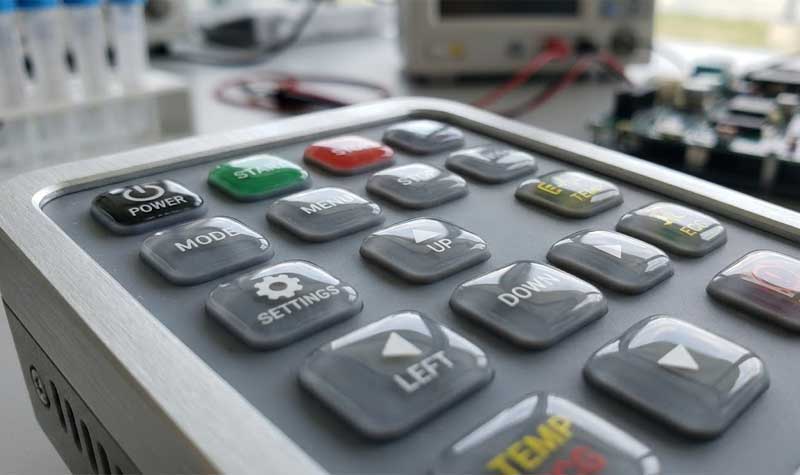 Epoxy Coating silicone keypad featuring various printed legends and icons set into a metal framed electronic control panel