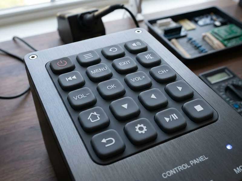 matte coated silicone keypad with custom printed icons integrated into a brushed metal control panel on a wooden workbench