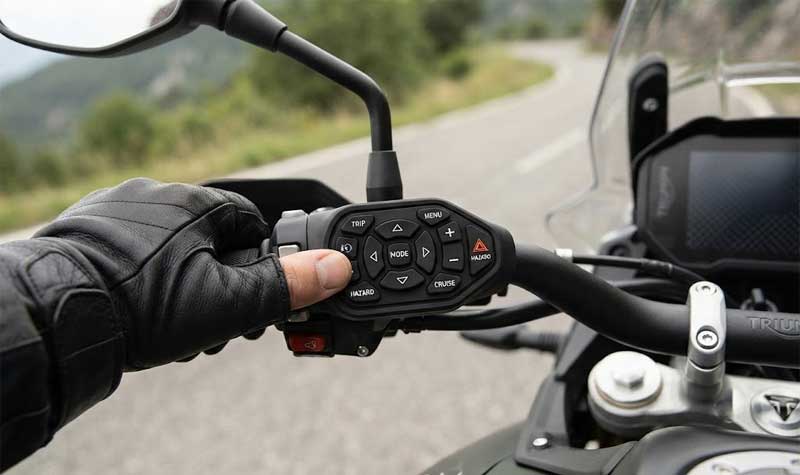 A rider uses their thumb to interact with a compact multi function Motorbike Silicone Keypad integrated directly onto the motorcycle handlebar