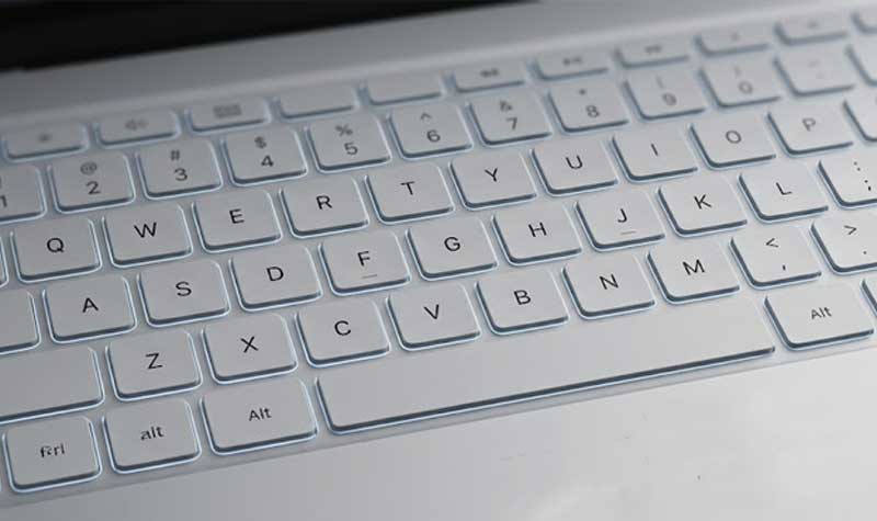 sleek white Laptop Silicone Keyboard featuring softly illuminated backlit keys on a minimalist silver laptop
