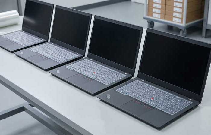 A row of identical enterprise laptops fitted with a clear Silicone Laptop Keyboard Cover arranged neatly on a clean worktable 1