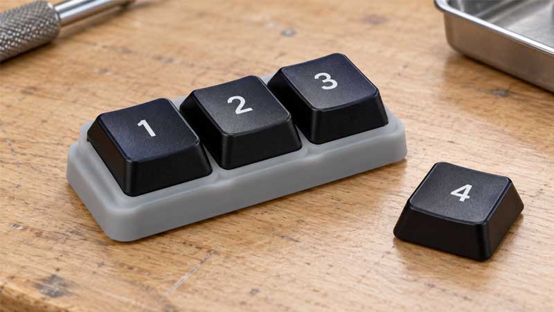 Plastic keycaps seated on a silicone keypad base beside a spare cap